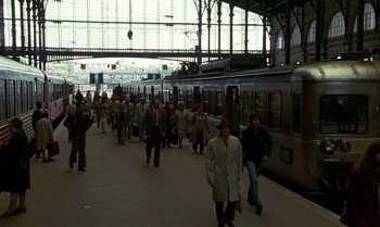 Movie still from “The Professional” (1981), directed by Georges Lautner – A group of people walking on a train platform; Extreme Wide shot, High angle