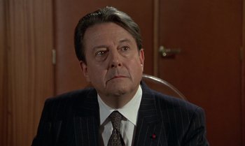 Movie still from “The Professional” (1981), directed by Georges Lautner – A person wearing a suit and tie; Close Up shot, Low angle