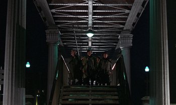 Movie still from “The Professional” (1981), directed by Georges Lautner – A group of people standing on a bridge at night; Wide shot, Low angle