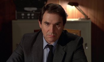 Movie still from “The Professional” (1981), directed by Georges Lautner – A person wearing a suit and tie; Close Up shot, Over the shoulder angle