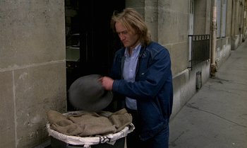 Movie still from “The Professional” (1981), directed by Georges Lautner – A man in a blue jacket is holding a plate; Medium shot, Low angle