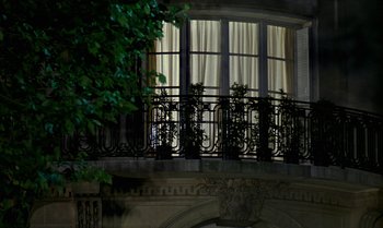Movie still from “The Professional” (1981), directed by Georges Lautner – A balcony in front of a large window with curtains; Extreme Wide shot, Low angle