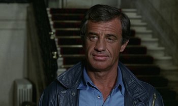 Movie still from “The Professional” (1981), directed by Georges Lautner – A person wearing a blue shirt; Close Up shot, Low angle