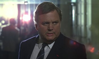 Movie still from “The Professional” (1981), directed by Georges Lautner – A man in a suit and tie looking at the camera; Close Up shot, Low angle