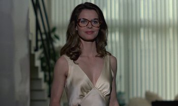 Movie still from “The Professional” (1981), directed by Georges Lautner – A woman in a white dress with glasses; Medium shot, Low angle