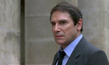 Movie still from “The Professional” (1981), directed by Georges Lautner – A person wearing a suit and tie; Close Up shot, Over the shoulder angle