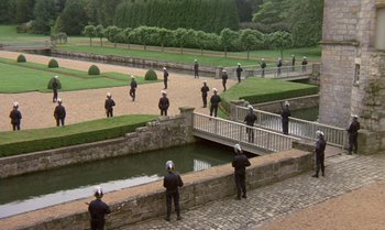 Movie still from “The Professional” (1981), directed by Georges Lautner – A group of people standing on a bridge near a pond; Extreme Wide shot, High angle