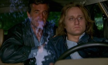 Movie still from “The Professional” (1981), directed by Georges Lautner – A man and a woman sitting in the back of a car; Medium shot, Over the shoulder angle