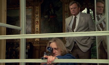 Movie still from “The Professional” (1981), directed by Georges Lautner – A man and a woman are looking through a window; Medium shot, Low angle