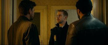 Movie still from “Journal 64” (2018), directed by Christoffer Boe – A man wearing a police uniform is talking to two other men; Medium shot, Over the shoulder angle