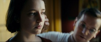Movie still from “Journal 64” (2018), directed by Christoffer Boe – A young woman is sitting in front of a window; Close Up shot, Over the shoulder angle
