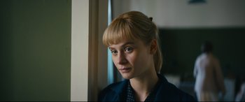 Movie still from “Journal 64” (2018), directed by Christoffer Boe – A woman with blonde hair and blue eyes looking out a window; Close Up shot, Over the shoulder angle