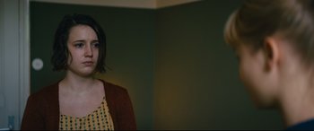 Movie still from “Journal 64” (2018), directed by Christoffer Boe – A woman standing next to a wall in a room; Close Up shot, Over the shoulder angle