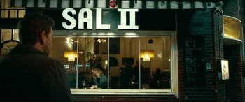Movie still from “Journal 64” (2018), directed by Christoffer Boe – A person sitting in a window of a restaurant; Wide shot, Over the shoulder angle