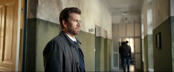 Movie still from “Journal 64” (2018), directed by Christoffer Boe – A man in a black jacket and a blue tie; Medium shot, Over the shoulder angle
