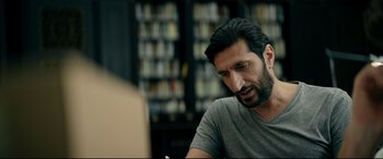Movie still from “Journal 64” (2018), directed by Christoffer Boe – A man sitting at a table in a library; Close Up shot, Low angle