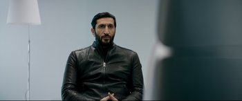 Movie still from “Journal 64” (2018), directed by Christoffer Boe – A man wearing a black leather jacket sitting in front of a mirror; Close Up shot, Over the shoulder angle