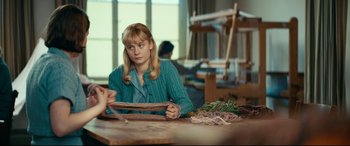 Movie still from “Journal 64” (2018), directed by Christoffer Boe – A woman sitting at a table in front of a wooden table; Medium shot, Over the shoulder angle
