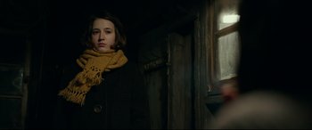 Movie still from “Journal 64” (2018), directed by Christoffer Boe – A young woman wearing a yellow scarf standing in front of a window; Close Up shot, Low angle