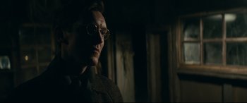 Movie still from “Journal 64” (2018), directed by Christoffer Boe – A man wearing glasses looking at the camera; Close Up shot, Low angle