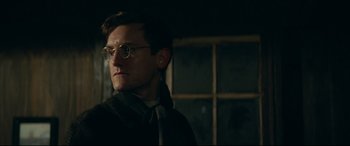 Movie still from “Journal 64” (2018), directed by Christoffer Boe – A man wearing glasses and a scarf looking to his left; Close Up shot, Low angle