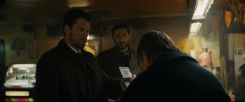 Movie still from “Journal 64” (2018), directed by Christoffer Boe – A group of men standing around each other; Medium shot, Over the shoulder angle