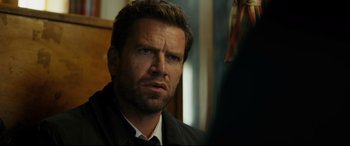 Movie still from “Journal 64” (2018), directed by Christoffer Boe – A person wearing a suit and tie; Close Up shot, Over the shoulder angle