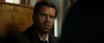 Movie still from “Journal 64” (2018), directed by Christoffer Boe – A person wearing a suit and tie; Close Up shot, Over the shoulder angle