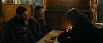 Movie still from “Journal 64” (2018), directed by Christoffer Boe – A man and a woman sitting at a wooden table; Medium shot, Over the shoulder angle