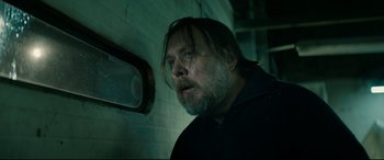 Movie still from “Journal 64” (2018), directed by Christoffer Boe – A man with long hair and a goatee looking out a window; Close Up shot, Low angle