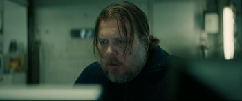 Movie still from “Journal 64” (2018), directed by Christoffer Boe – A man with long hair and a goatee looking at a computer screen; Close Up shot, Over the shoulder angle