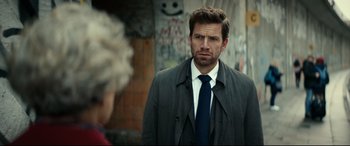 Movie still from “Journal 64” (2018), directed by Christoffer Boe – A man wearing a suit and tie standing in front of a woman; Close Up shot, Over the shoulder angle