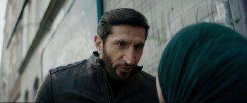 Movie still from “Journal 64” (2018), directed by Christoffer Boe – A person wearing a jacket; Close Up shot, Over the shoulder angle