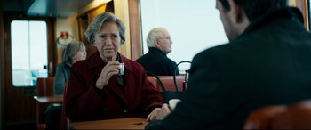 Movie still from “Journal 64” (2018), directed by Christoffer Boe – An older woman sitting at a table in front of an older man; Close Up shot, Over the shoulder angle