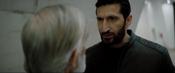 Movie still from “Journal 64” (2018), directed by Christoffer Boe – A man talking to another man in front of a wall; Close Up shot, Over the shoulder angle