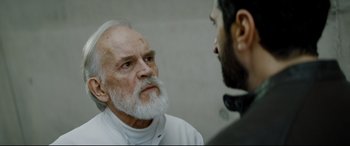 Movie still from “Journal 64” (2018), directed by Christoffer Boe – An old man with a beard and a beard mustache and a white beard is talking to a younger man; Close Up shot, Over the shoulder angle
