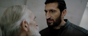 Movie still from “Journal 64” (2018), directed by Christoffer Boe – A man with a long beard and a man with a long beard; Close Up shot, Over the shoulder angle