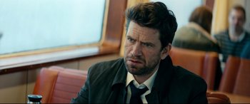 Movie still from “Journal 64” (2018), directed by Christoffer Boe – A person wearing a suit and tie; Close Up shot, Over the shoulder angle