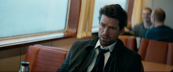 Movie still from “Journal 64” (2018), directed by Christoffer Boe – A person wearing a suit and tie; Close Up shot, Over the shoulder angle