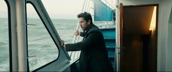 Movie still from “Journal 64” (2018), directed by Christoffer Boe – A man standing on a boat looking out the window; Medium shot, Over the shoulder angle