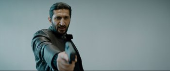 Movie still from “Journal 64” (2018), directed by Christoffer Boe – A man holding a gun in his right hand; Close Up shot, Low angle