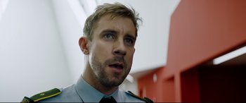 Movie still from “Journal 64” (2018), directed by Christoffer Boe – A person wearing a uniform; Close Up shot, Low angle