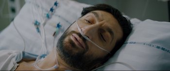 Movie still from “Journal 64” (2018), directed by Christoffer Boe – A man with a beard is laying in a hospital bed; Close Up shot, High angle