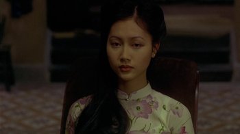 Movie still from “The Quiet American” (2002), directed by Phillip Noyce – A woman with long black hair sitting in a chair; Close Up shot, High angle