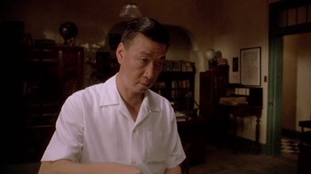 Movie still from “The Quiet American” (2002), directed by Phillip Noyce – An older man in a white shirt is looking at the camera; Medium shot, Low angle
