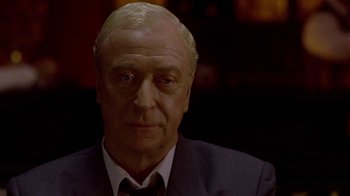 Movie still from “The Quiet American” (2002), directed by Phillip Noyce – An older man wearing a suit and tie; Close Up shot, Over the shoulder angle