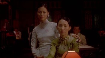 Movie still from “The Quiet American” (2002), directed by Phillip Noyce – Two women are posing for a picture at a restaurant; Medium shot, Over the shoulder angle