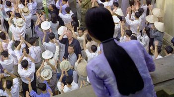 Movie still from “The Quiet American” (2002), directed by Phillip Noyce – A group of people standing around each other in a crowd; Wide shot, Over the shoulder angle