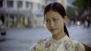 Movie still from “The Quiet American” (2002), directed by Phillip Noyce – A young woman wearing a floral dress and a pearl necklace; Close Up shot, Low angle
