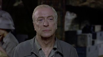 Movie still from “The Quiet American” (2002), directed by Phillip Noyce – An older man with white hair is looking at the camera; Close Up shot, Over the shoulder angle